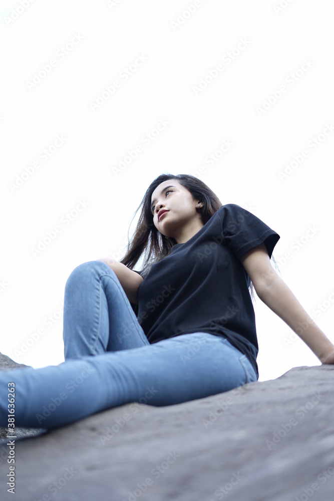 photographing a model of a girl sitting on a large rock wearing a black t-shirt and jeans. black t-shirt models for mockups and templates. photographing a model of a girl sitting on a large rock wearing a black t-shirt and jeans. black t-shirt models for mockups and templates.