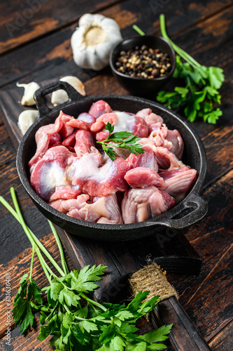 Raw uncooked chicken gizzards, stomach in a pan. Dark wooden background. Top view