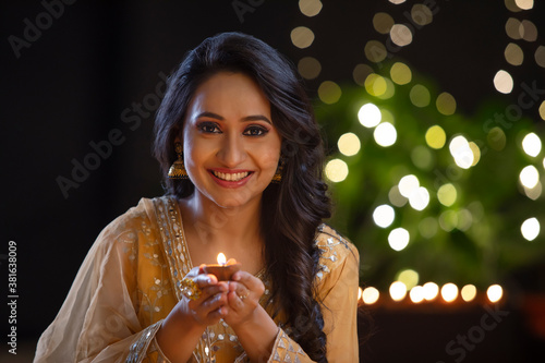 Woman smiling with a diya in her hand on the occasion of Diwali	 photo