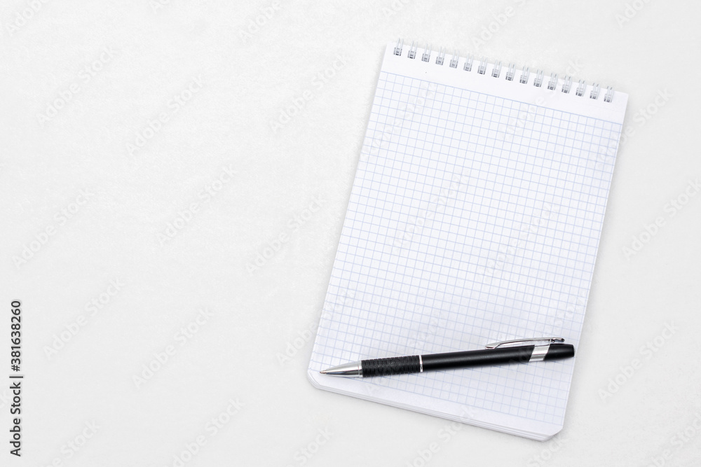 Spiral white notepad and ballpoint pen, top view, white background, copy space Spiral white notepad and ballpoint pen, top view, white background, copy space