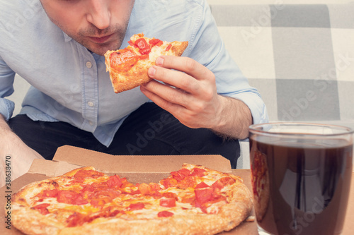 Bild auf Leinwand Guy eats a slice of pizza from a plate, male hands, cropped image, close-up