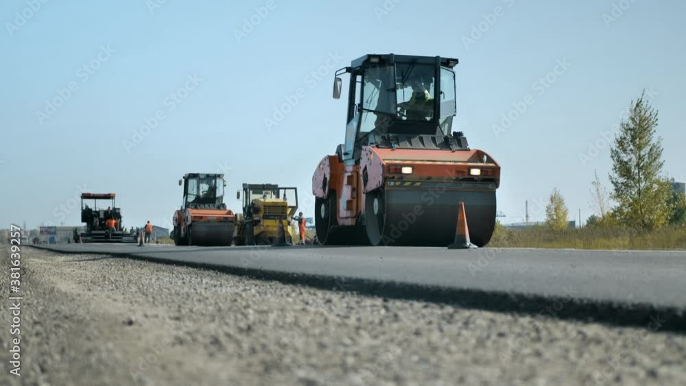 Road rollers level and compact the asphalt against the blue sky. A layer of freshly laid asphalt. Road surface repair. Road repair. Road construction machinery. Road rollers level and compact the asphalt against the blue sky. A layer of freshly laid asphalt. Road surface repair. Road repair. Road construction machinery.