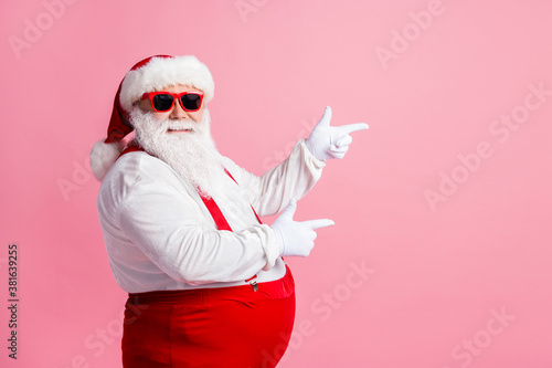 Profile side photo of funny fat overweight santa claus point index finger copyspace x-mas adverts wear overalls suspenders headwear sunglass isolated over pastel color background