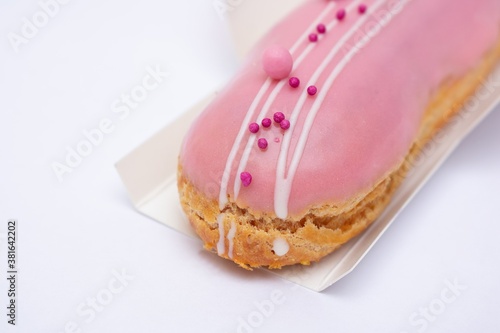 Pink eclair with pink glaze on white background, close-up, cropped image. Food concept. Top view