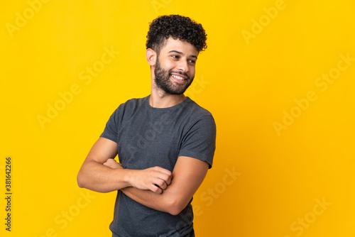 Young Moroccan man isolated on yellow background with arms crossed and happy