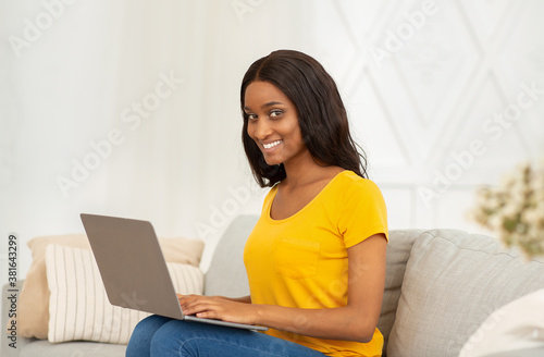 Positive black businesswoman using laptop for distance work, education or communication at home © Prostock-studio