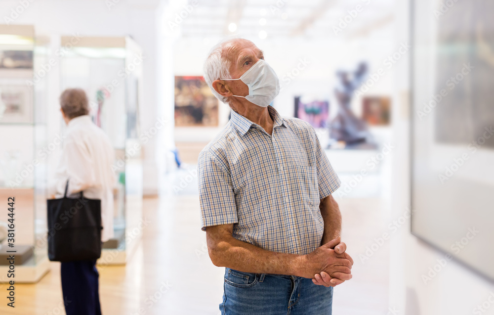 Fototapeta premium mature European man examines paintings in an exhibition in hall of an art museum
