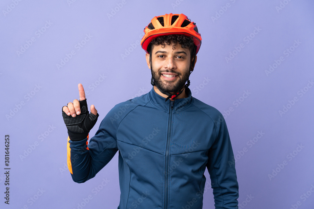 Young Moroccan cyclist man isolated on purple background showing and lifting a finger in sign of the best Young Moroccan cyclist man isolated on purple background showing and lifting a finger in sign of the best