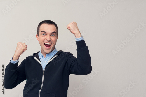Happy young man shouts: Hooray! Yes! White background, copy space photo