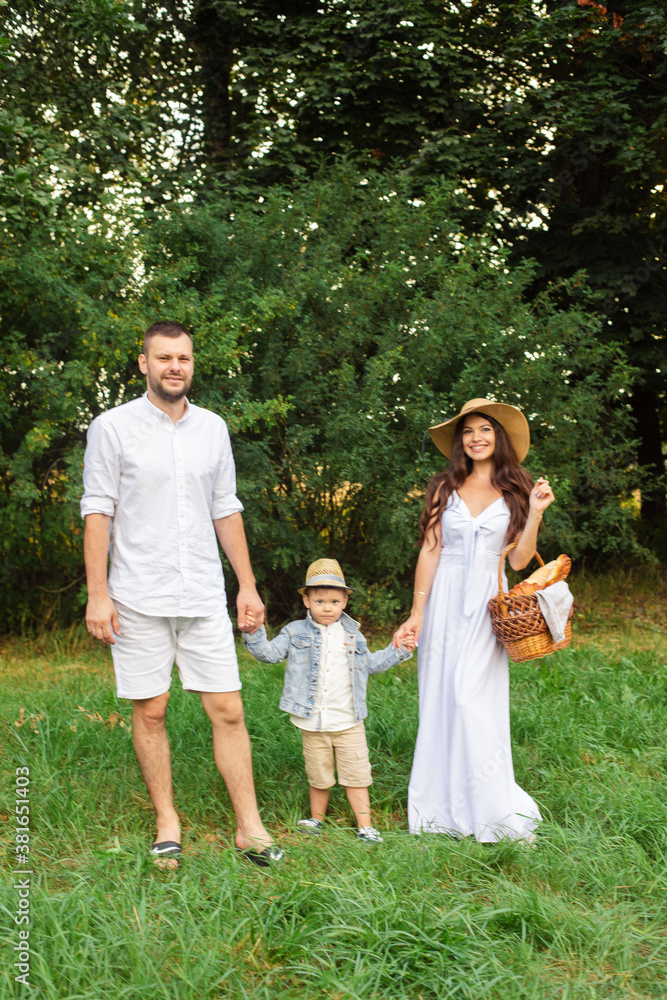 Smiling young father and mother standing with their little son while enjoying summer day weekend. Family and leisure concept Smiling young father and mother standing with their little son while enjoying summer day weekend. Family and leisure concept