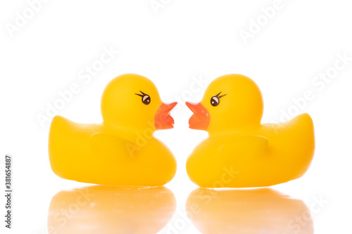 Two mini yellow rubber ducks turned to each other isolated on white background. Ducklings love, bath baby toy, funny kids game. Relationship, couple, Valentine's day postcard concept. Copy text space