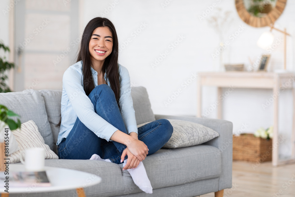 Portrait of relaxed smiling korean lady posing on sofa at home Portrait of relaxed smiling korean lady posing on sofa at home