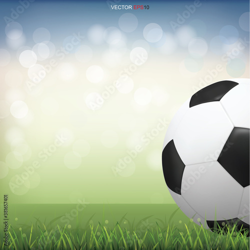 Soccer football ball on green grass field with light blurred bokeh background. Vector.