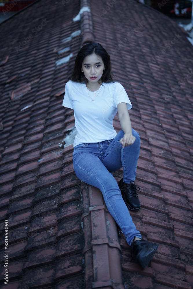 The blonde girl sits on the roof tile in a style wearing a white t-shirt. female t-shirt models for mockups and templates. The blonde girl sits on the roof tile in a style wearing a white t-shirt. female t-shirt models for mockups and templates.