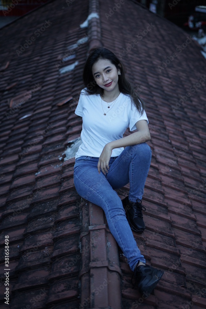 The blonde girl sits on the roof tile in a style wearing a white t-shirt. female t-shirt models for mockups and templates. The blonde girl sits on the roof tile in a style wearing a white t-shirt. female t-shirt models for mockups and templates.