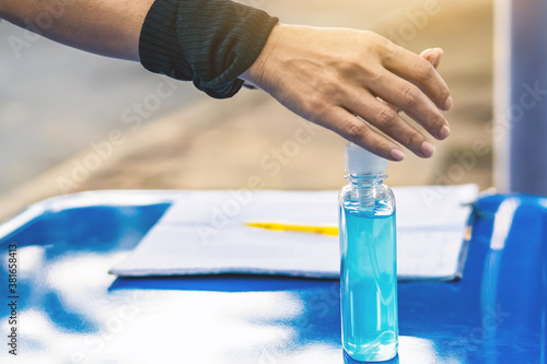 Blue alcohol gel bottle and a register book on the table for athletes to prevent Corona Virus (COVID -19) infection and spread before exercising in public park. New normal lifestyle. Selective focus