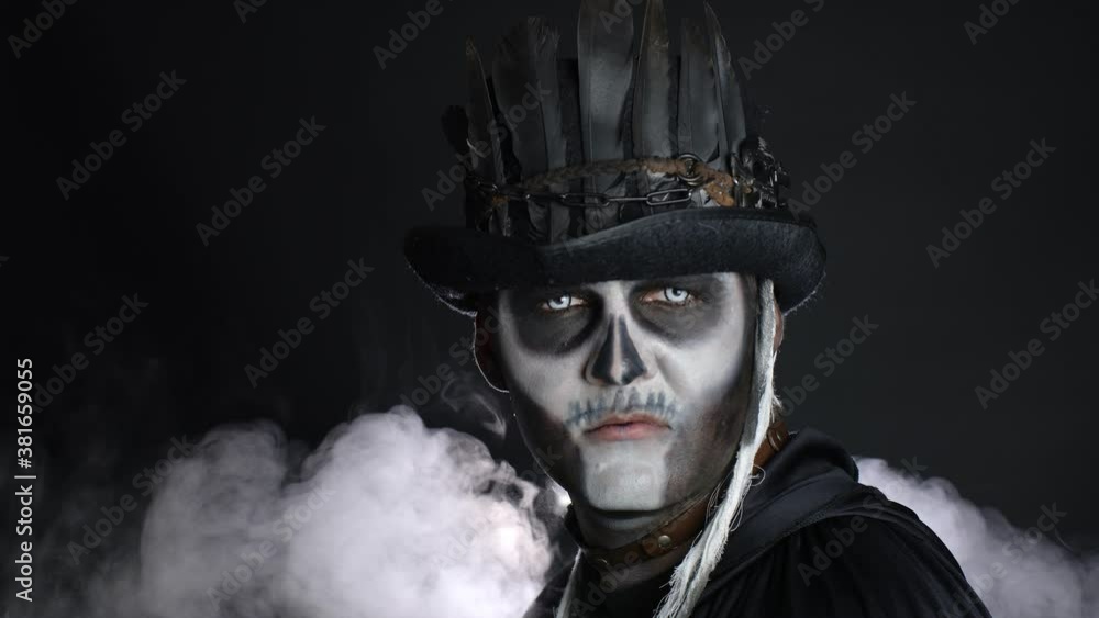Creepy man with skeleton makeup appearing from darkness when light falls on him, making faces Creepy man with skeleton makeup appearing from darkness when light falls on him, making faces
