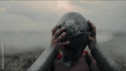 Spartan putting helmet up from dry grass.