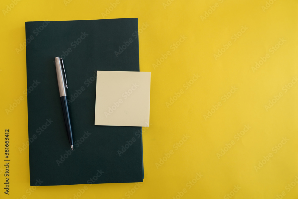 Dark green book with pen and sticky notes on yellow flat background. Dark green book with pen and sticky notes on yellow flat background.