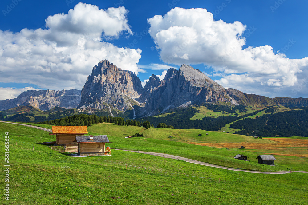 Famous Alpe di Siusi - Seiser Alm with Sassolungo - Langkofel mountain group in background at sunset. Wooden chalets in Dolomites, Trentino Alto Adige region, South Tyrol, Italy
