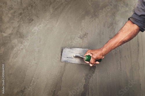 Concrete plasterers to create industrial workers background walls with plastering tools.