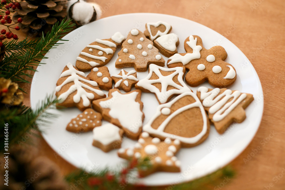 Christmas gingerbread cookies on white plate on wooden background with fir branches Christmas gingerbread cookies on white plate on wooden background with fir branches