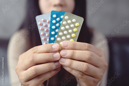 Women holding birth control pills, focus hand