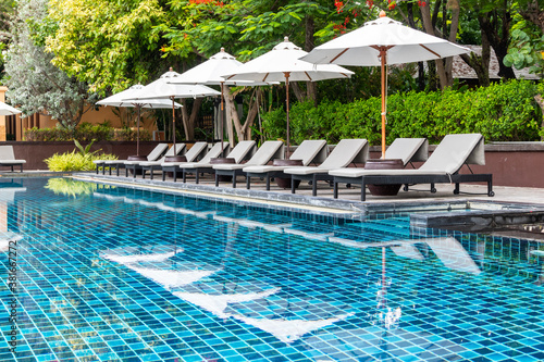 White umbrella and outdoor beds next to swimming pool