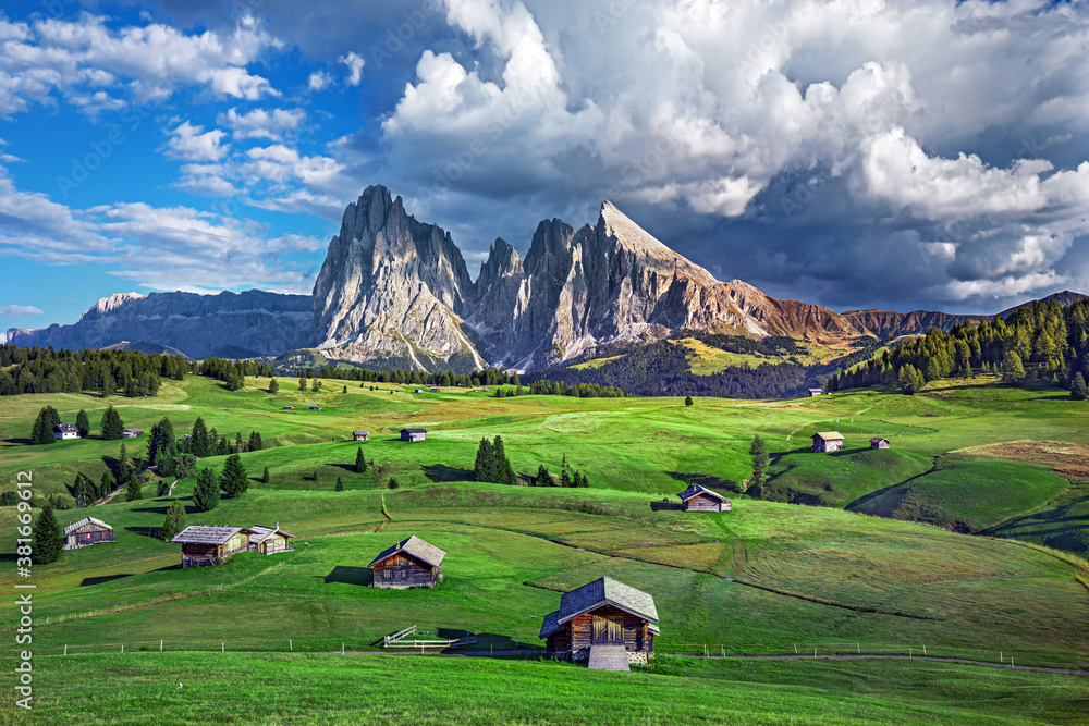 Famous Alpe di Siusi - Seiser Alm with Sassolungo - Langkofel mountain group in background at sunset. Wooden chalets in Dolomites, Trentino Alto Adige region, South Tyrol, Italy Famous Alpe di Siusi - Seiser Alm with Sassolungo - Langkofel mountain group in background at sunset. Wooden chalets in Dolomites, Trentino Alto Adige region, South Tyrol, Italy