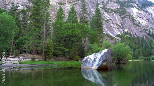 Yosemite National Park reflection in Merced River of Yosemite waterfalls and beautiful mountain landscape in California USA. amazing rocky hills and pine trees on the other side of mirror lake.