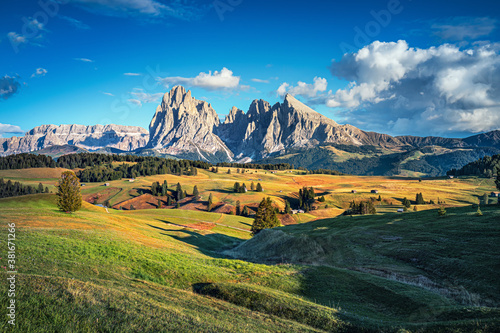 Famous Alpe di Siusi - Seiser Alm with Sassolungo - Langkofel mountain group in background at sunset. Wooden chalets in Dolomites, Trentino Alto Adige region, South Tyrol, Italy