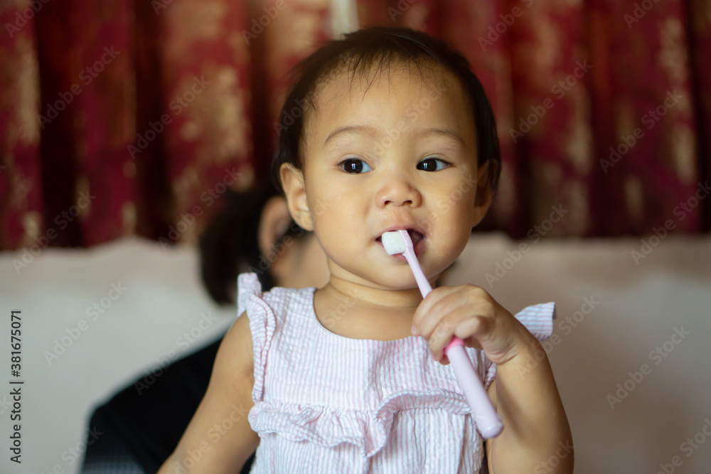 11-month-old girl practicing a toothbrush by herself from her mother's teaching.