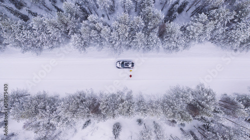 Aerial view, couple of travelers stopped on road during winter trip, car is broken and stands on the emergency gang while waiting for a tow truck covered by insurance