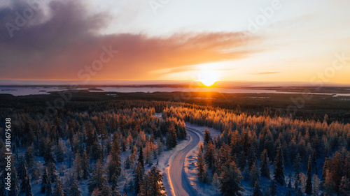 Aerial view from drone of snowy pines of endless coniferous forest trees in Lapland National park, bird’s eye scenery  view of natural landmark in Riisitunturi on winter season at sunset golden light