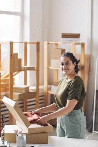 Portrait of young woman packing new clothes she making parcels for delivery working in webstore