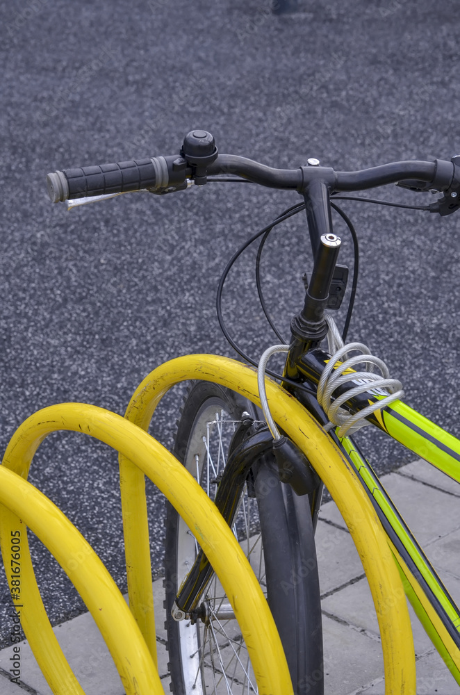 Handlebar and frame of a sports bicycle strapped to a parking place close up Handlebar and frame of a sports bicycle strapped to a parking place close up