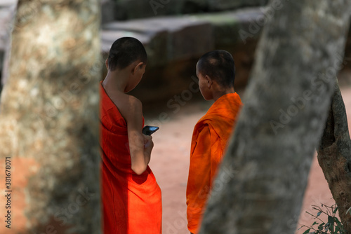 Focusing on unidentified two monks is using the mobile phone at Ta Prohm Temple, Siem Reap, Cambodia. photo