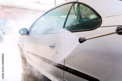 Washing car with pressure washer at self-service car wash station