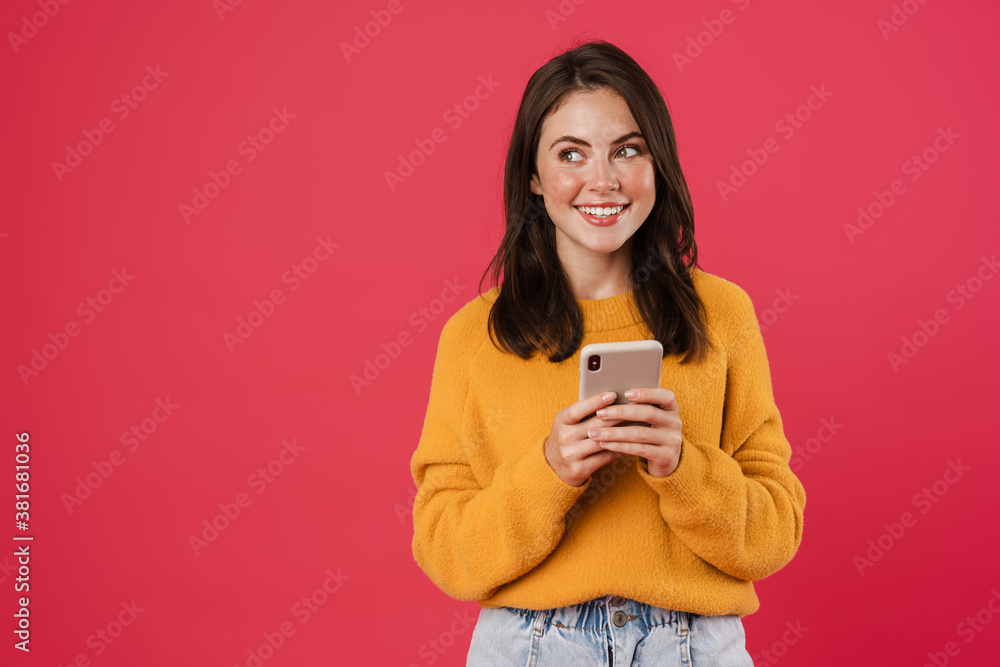 Image of joyful brunette girl smiling and using cellphone Image of joyful brunette girl smiling and using cellphone
