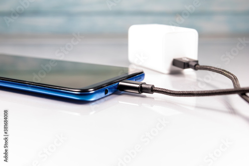 Charging cable for smartphone plugged into a white background