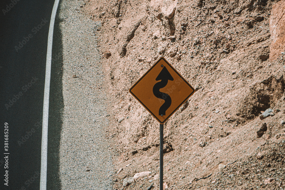 Warning sign at the long curvy road leading into nothing in the death valley Warning sign at the long curvy road leading into nothing in the death valley