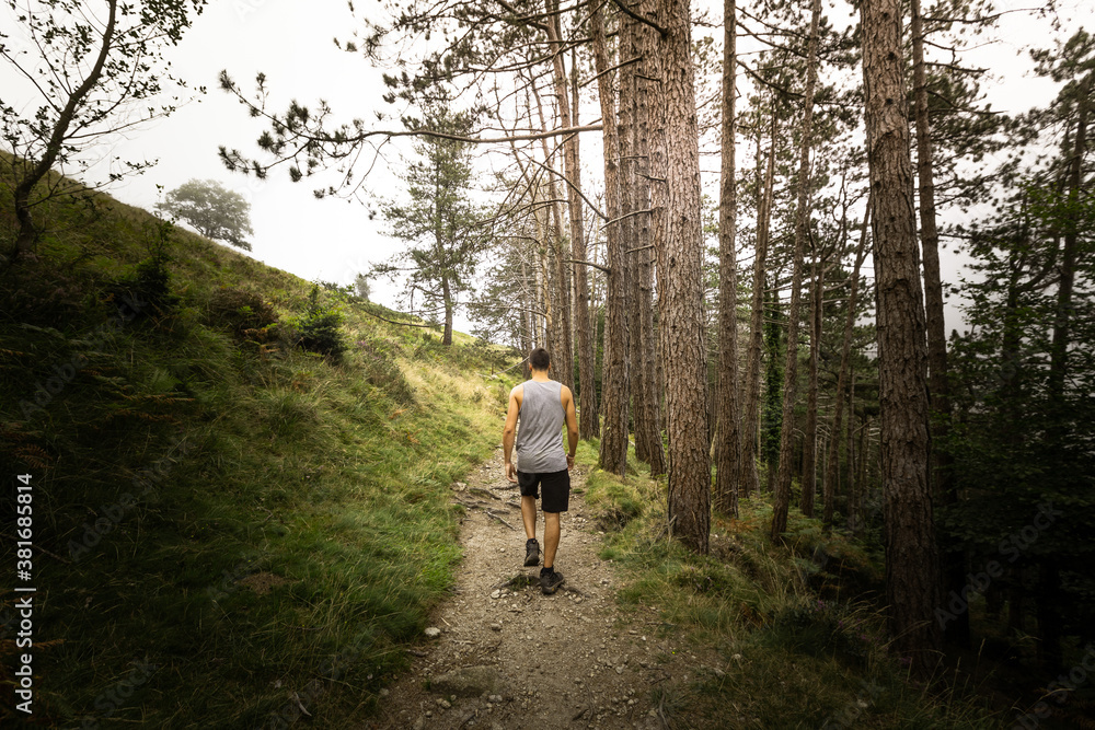 Young caucasian man exploring a foggy forest in Artikutza, Basque Country.