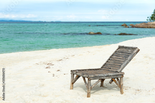 Wooden beach chair on white sand beach in Thailand.