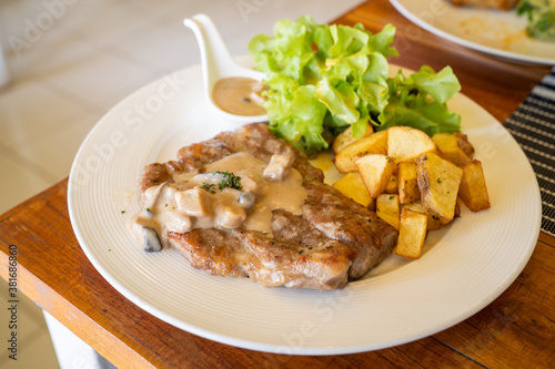 T-bone steak, a prepared piece of grilled T-bone steak brown sauce with mashed potato and vegetable on dining table