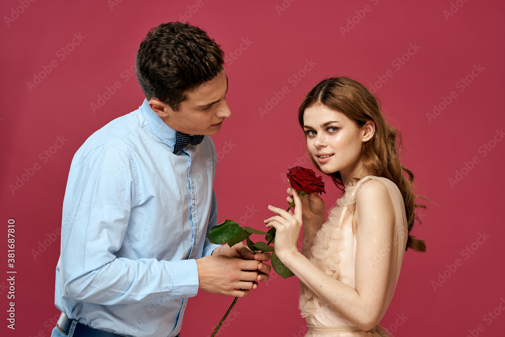 enamored man and woman with a red flower on a pink background hug each other Copy Space enamored man and woman with a red flower on a pink background hug each other Copy Space