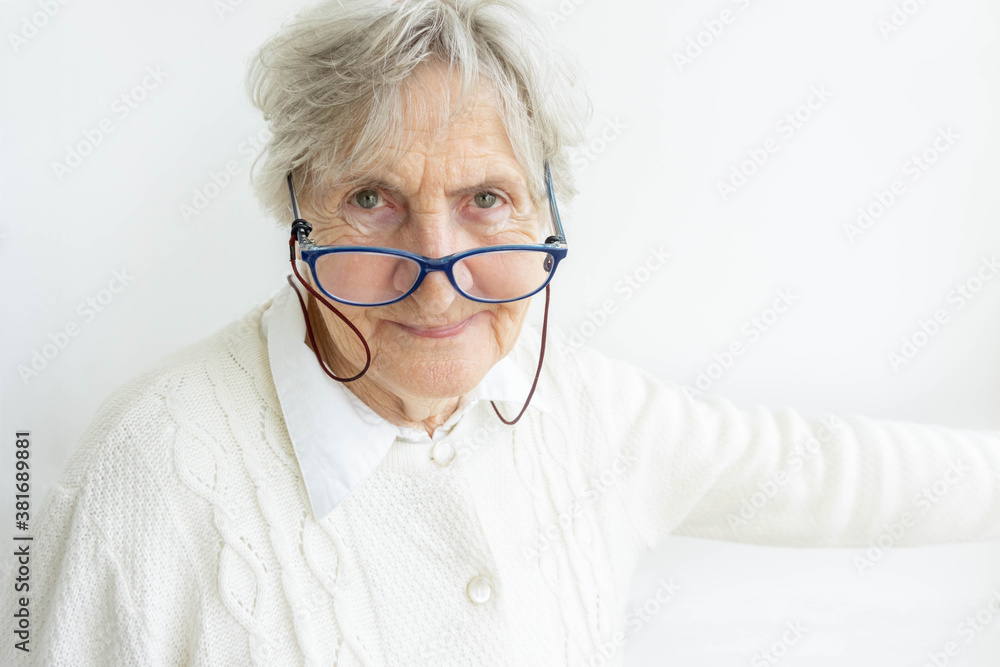 Gray hair senior lady in glasses on white wall background