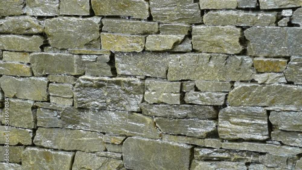 Slow motion close up water trickling down stone brick wall Slow motion close up water trickling down stone brick wall