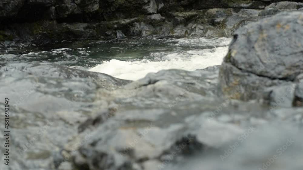Slow motion water rushing over rocks in canyon with light rainfall Slow motion water rushing over rocks in canyon with light rainfall