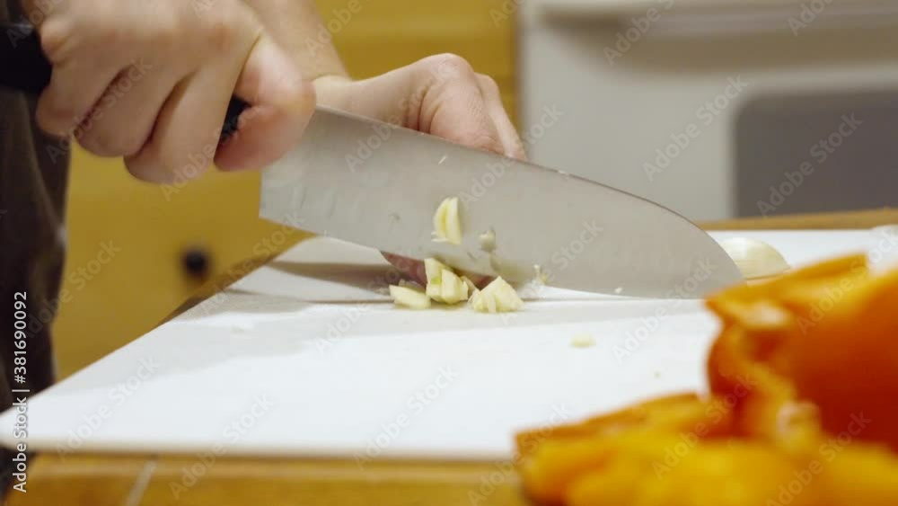 Close up mincing garlic clove with knife on cutting board Close up mincing garlic clove with knife on cutting board