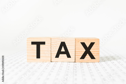 words TAX on wooden cubes, white background. business concept